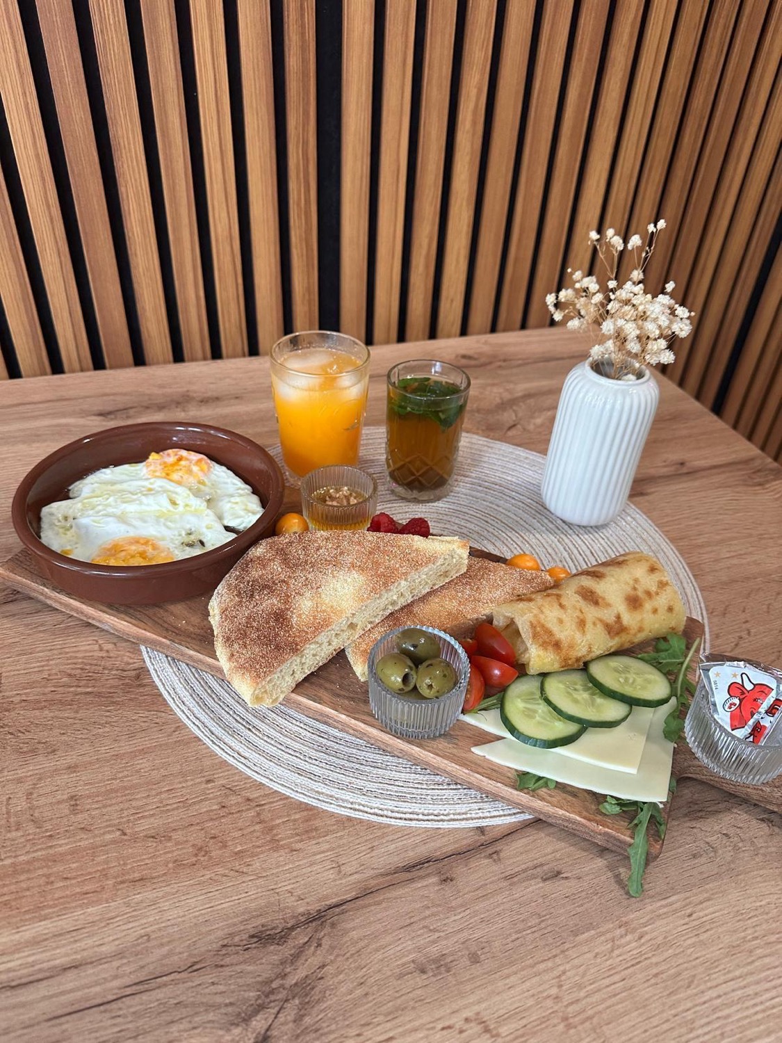 Marokkanisches Frühstück auf Holzbrett mit Tajine, Msemen, Briouat und Minztee