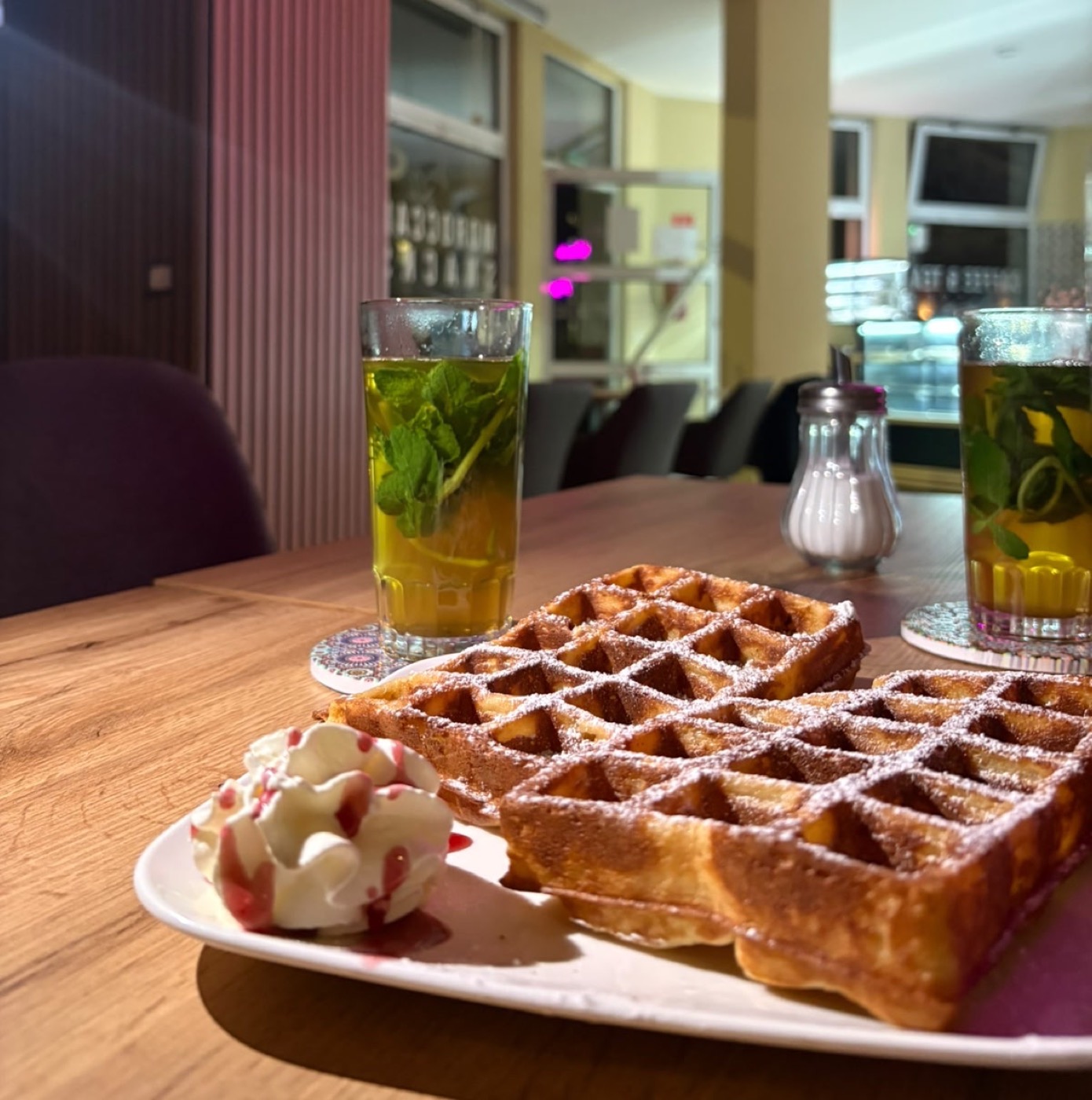 Belgische Waffeln mit Puderzucker, Sahne und Himbeersauce